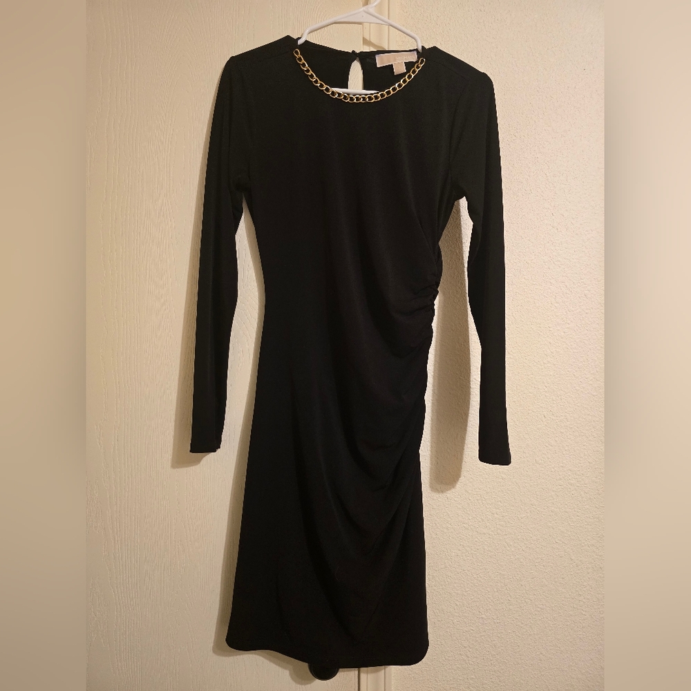 Michael Kors black knee-length dress with gold chain accessories.